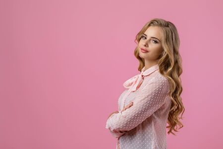 Portrait of beautiful tender curly blonde woman in pink shirt on pink background. copy spaceの写真素材