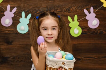 happy little child girl holding basket with painted Easter eggs. Easter dayの写真素材