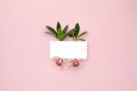 layout made with green leaves and orchid flowers on pink pastel background. Tropical nature concept. Flat lay. empty space for text. mock up with copy space.の写真素材