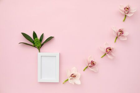 photo frame decorated with green leaves on pink pastel background. empty space for text. mock up with copy spaceの写真素材