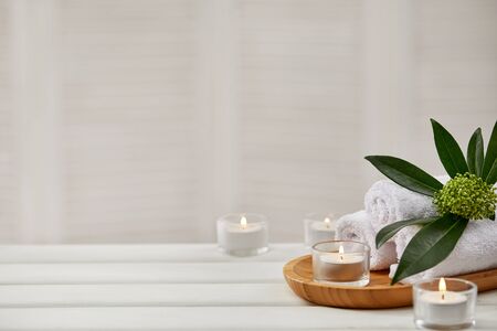Spa composition with aromatic candles and towel on white wooden table. Beauty spa treatment. copy spaceの写真素材