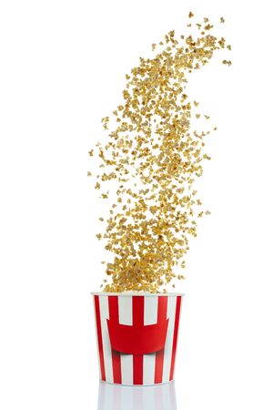 Flying popcorn from red and white paper striped bucket isolated over the white background. Cinema style popcornの写真素材
