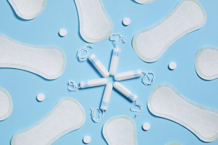 clean white sanitary cotton pads and tampons on blue background. Pattern of Feminine hygiene productsの写真素材
