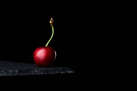 sweet ripe red cherry on black background with copy space