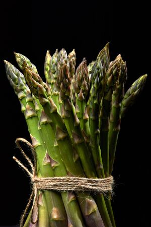 bunch of fresh green asparagus with rope on black backgroundの写真素材