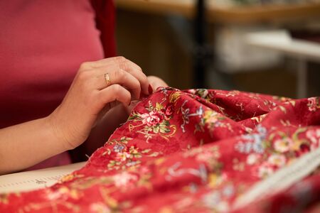 tailor woman sews red dress. Tailor working in her tailor shopの写真素材