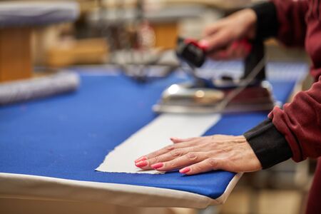 Tailor ironing the fabric. seamstress irons dress in a sewing workshopの写真素材