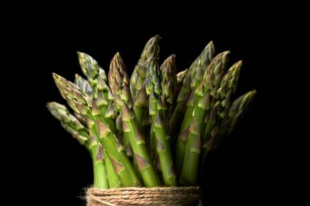 bunch of fresh green asparagus with rope on black backgroundの写真素材