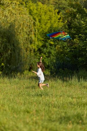 happy cute little child girl launches kite in park in sunny summer day. carefree timeの写真素材