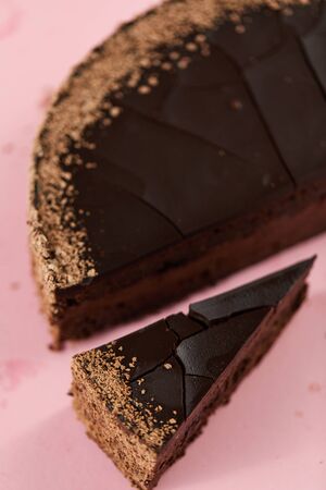 tasty homemade chocolate cake with cut piece on pink backgroundの写真素材