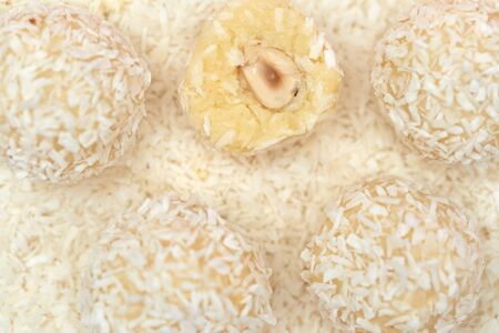 close-up, candies covered by shredded coconut. coconut balls with coconut flakes. top view