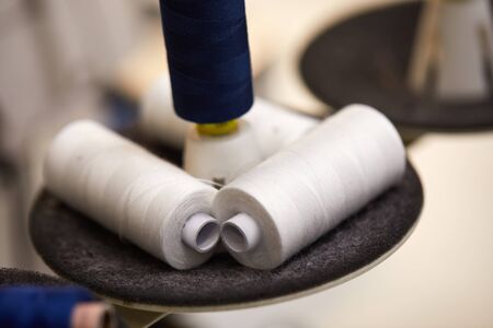 cotton thread rolls for sewing machine. blue and white thread spools for garment industryの写真素材