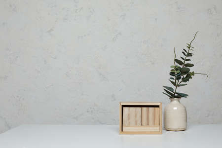 Blank wooden calendar and vase with plant on white table. Mockup. Empty desk calendar. copy spaceの写真素材