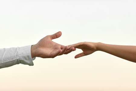 man and woman hand touch each other. couple holding together on sky backgroundの写真素材