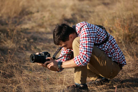 young man photpgrapher talking pictures outdoors on the sunsetの写真素材