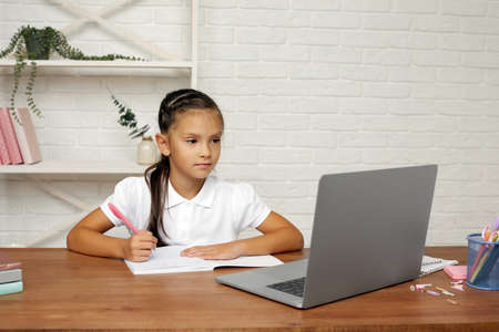happy little child girl using laptop computer, studying through online e-learning system.