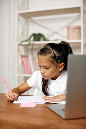 happy little child girl using laptop computer for studying online e-learning system. online...