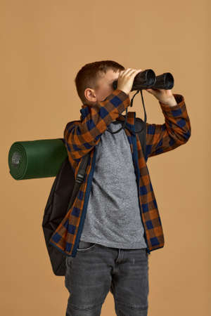 Little boy tourist looking into the distance with binoculars