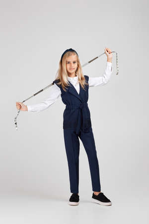 happy little girl holding tape measure on studio background. the child dreams of becoming a tailor or fashion designer. Full lengthの写真素材