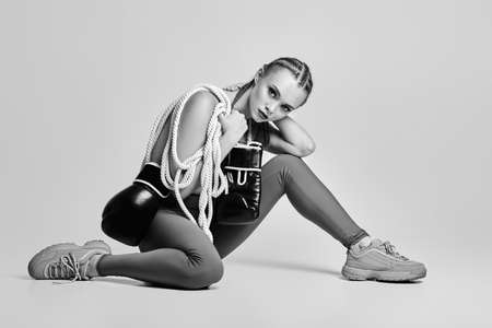 fashion sexy gorgeous woman model with black boxing gloves and white ropesitting on floor. Glamour...