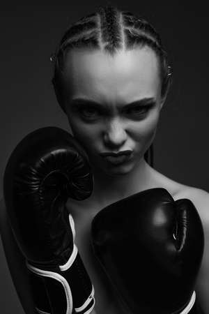 portrait of glamour female boxer looking at the camera. fashion sexy gorgeous woman model in black boxing gloves on studio background. black and whiteの写真素材