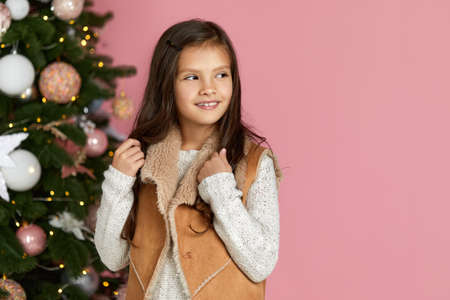 portrait of cute joyful little child girl on background of christmas tree. copy space for text