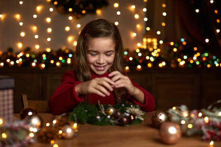 happy cute little child girl makes a handmade Christmas wreath at home.の写真素材