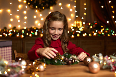 happy cute little child girl decorating Christmas wreath at home.の写真素材
