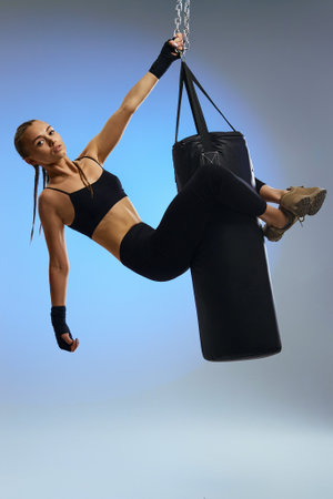 fit beautiful woman with boxing bandages and punching bag on studio background. full lenth