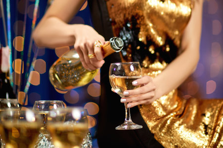 close-up of female hand with is pouring champagne into a glass. party and holiday celebrationの写真素材