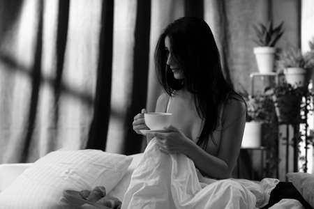 beautiful young woman drinking her tea in her bedroom in the morningの写真素材