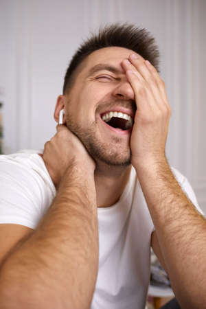 man laughs. portrait of handsome young man in earphones is talking to somebody on video call.の写真素材