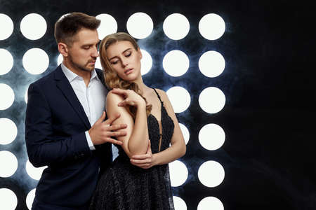 glamorous luxurious couple posing against the backdrop of spotlights and smoke. night life. copy...