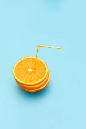 fresh orange with straw. Orange cut in half on blue background.の写真素材