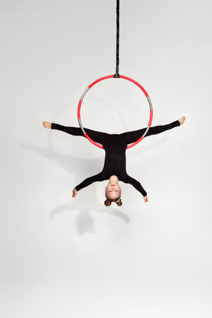Little acrobat girl in black sportwear doing twine on an aerial hoopの写真素材