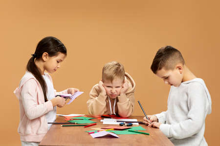 happy children cutting colored papers with scissors