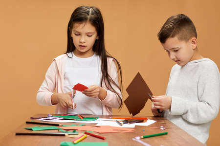 happy children cutting colored papers with scissorsの写真素材