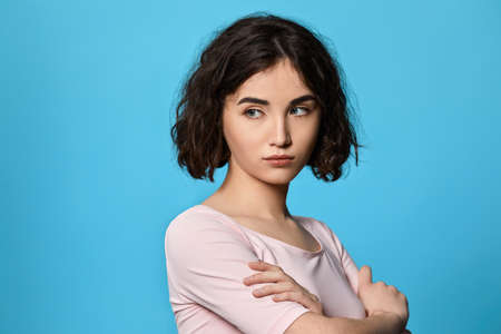 sad curly young brunette woman on blue background.の写真素材