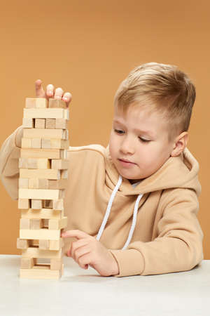 children plays with wooden constructor on desk.の写真素材