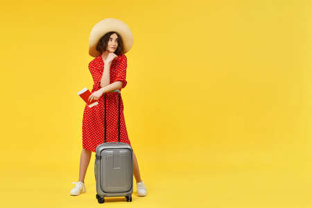 woman with suitcase going traveling on yellow background.の写真素材