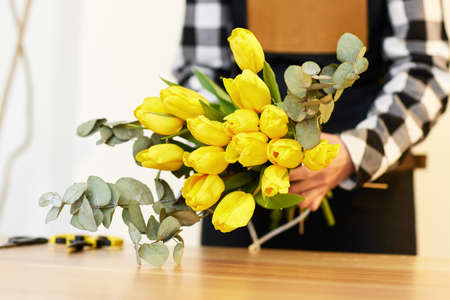 Florist makes a bouquet of fresh yellow tulips.の写真素材