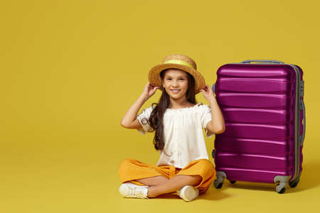 little girl with suitcase and passport sitting on floorの写真素材