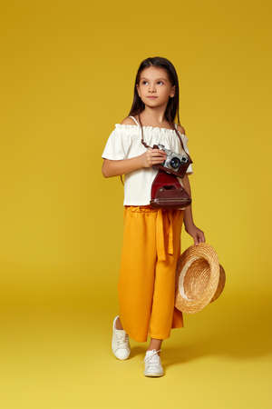 cute little girl with retro camera on yellow background.の写真素材
