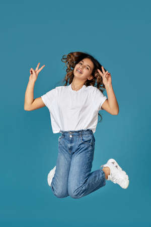 curly teen girl in white t-shirt and denim jumping