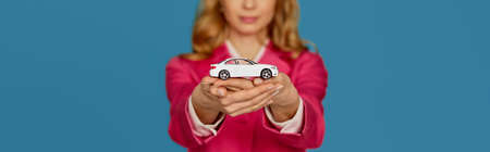 beautiful blonde woman in pink jacket holding a little car
