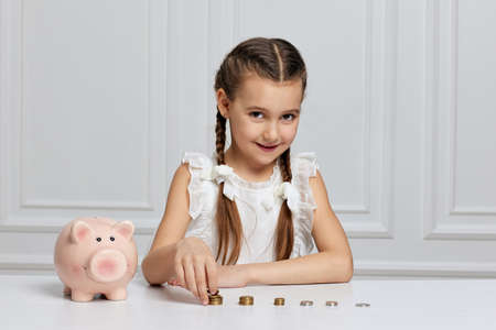 Little child girl with piggy bank at homeの写真素材