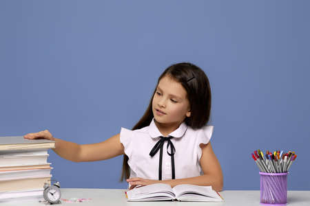 happy schoolgirl studying with a pile of books