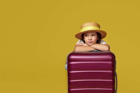 child with pink suitcase on yellow background.の写真素材