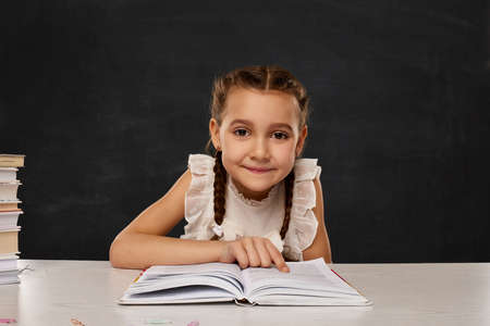 little child girl reading a book in the classroomの写真素材