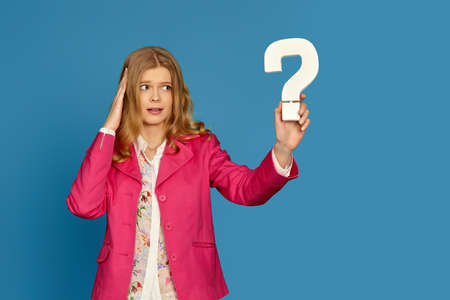 blonde woman in pink jacket holding question markの写真素材